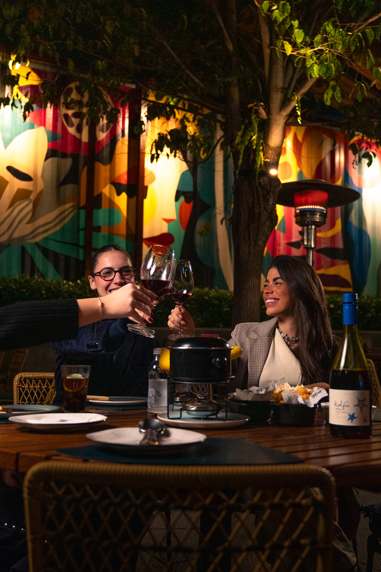 Casal brindando com vinho no terraço do Smeat à noite
